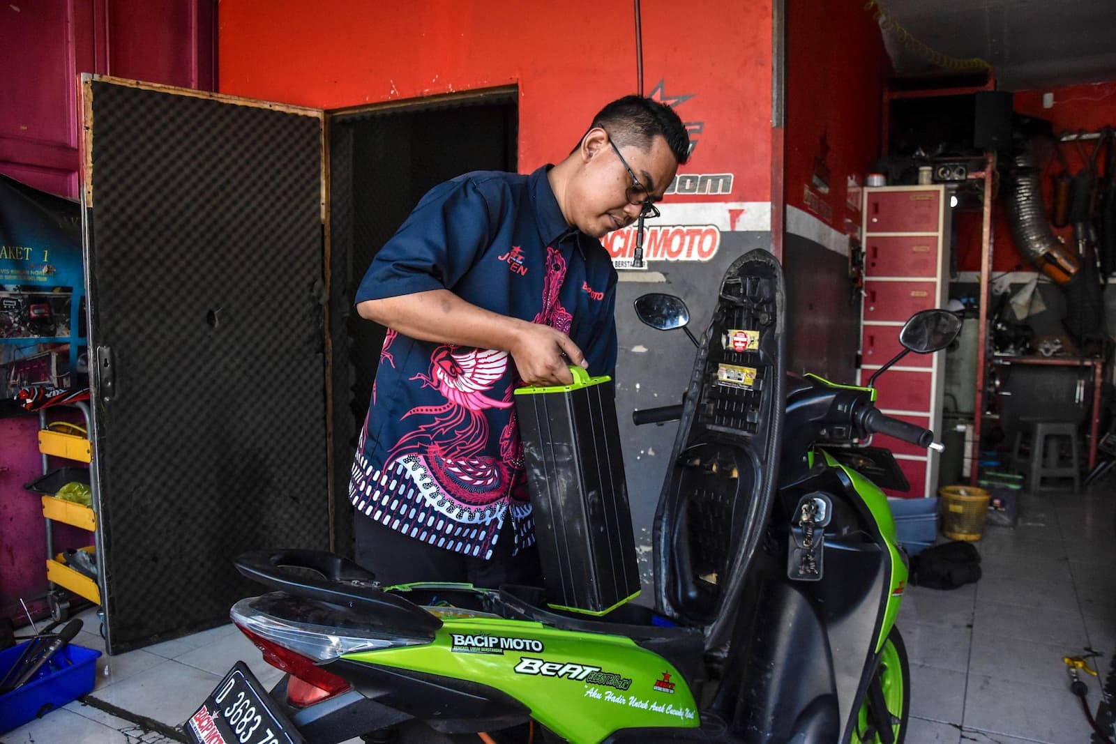 A mechanic in the Indonesian city of Bandung, West Java, replaces the battery of an electric moped