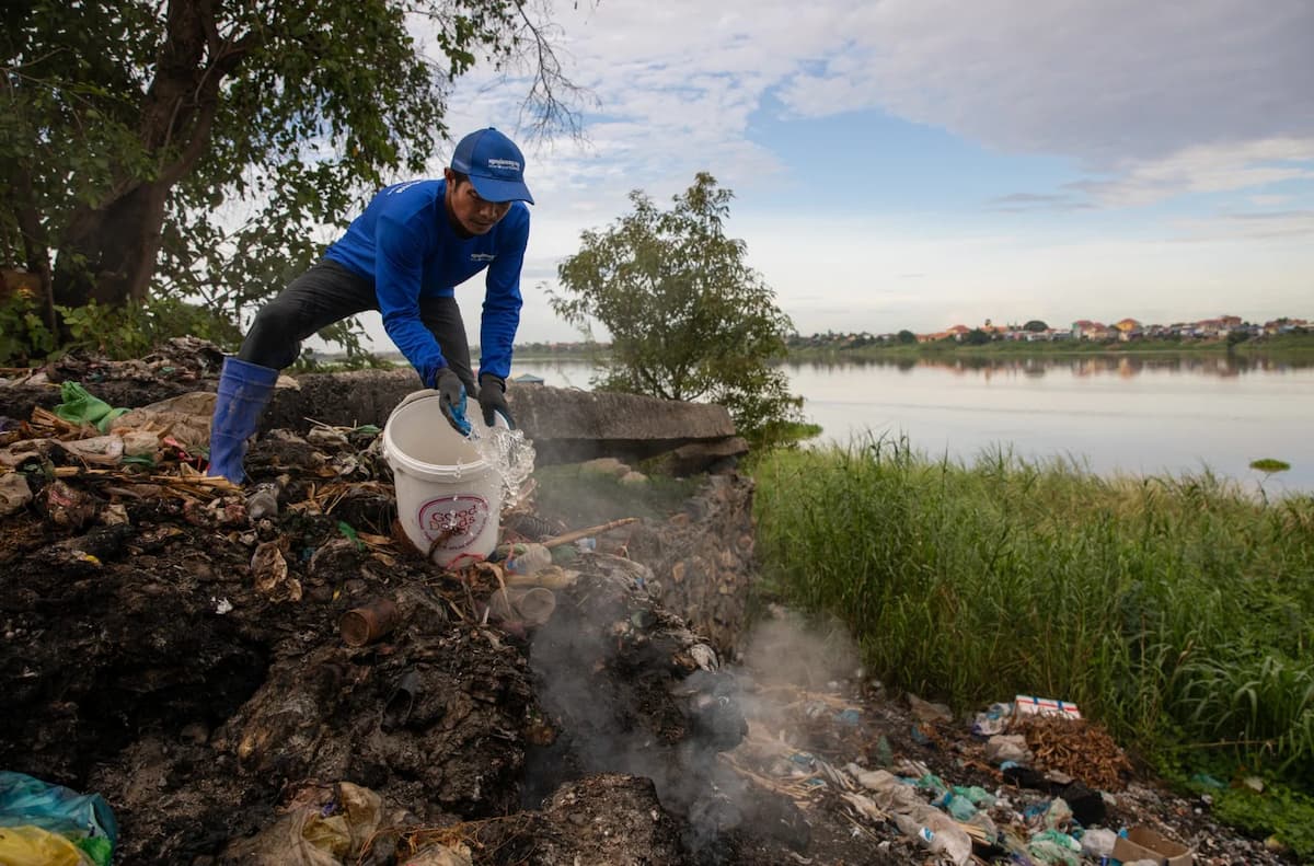 A volunteer douses a burning pile of rubbish at an unofficial dump site next to the Tonle Sap River in Cambodia. The lack of proper waste management exacerbates the problem of plastic pollution in most Mekong countries (Image: Anton L. Delgado / Dialogue Earth)