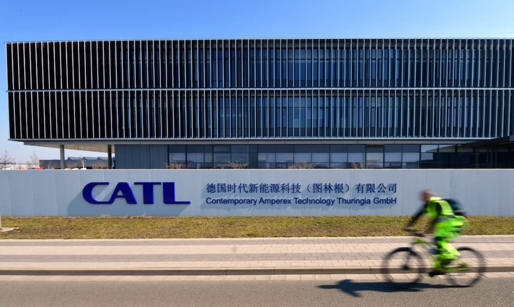 A worker cycles past a CATL battery cell factory near Arnstadt, Germany (Image: Martin Schutt / dpa / Alamy)