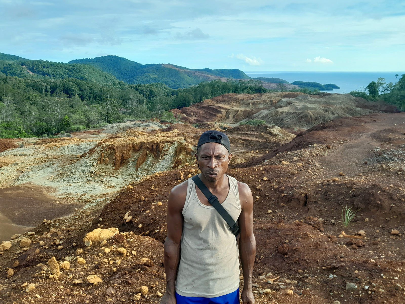 Arif, a resident of Sonof Kacepo village, stands on Kaf Hill. Large swathes have suffered severe deforestation and been reduced to rubble from nickel mining excavations (Image: Rabul Sawal / Project Multatuli)