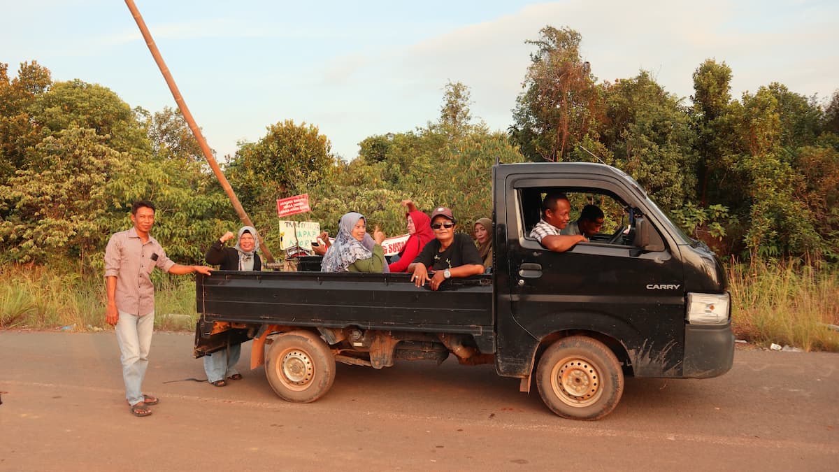 Rempang Island residents ride in a pickup truck while holding signs in protest against the relocation. One sign reads: “Don’t rob our children of their future” (Image: Bagus Pradana / Transparansi Internasional Indonesia)
