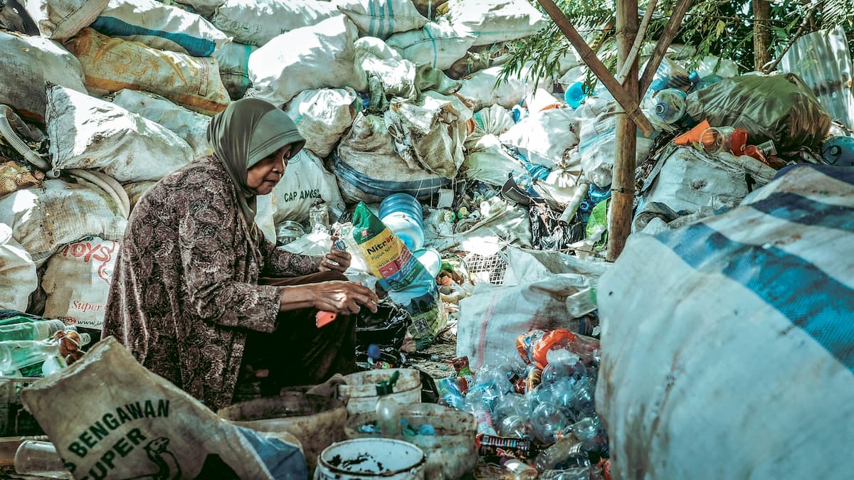 A woman sits under a tree surrounded by dry waste in Indonesia’s East Java province. Image by Bamban heru via Unsplash