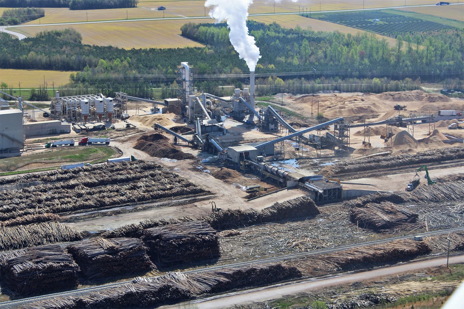 Smokestack emissions at the Enviva Northampton, North Carolina, wood pellet mill. A steady flow of tractor trailer trucks arrive at wood pellet plants daily carrying whole logs and wood chips sourced from surrounding rural areas. The mills cause air pollution linked to respiratory ailments. Image courtesy of the Dogwood Alliance.