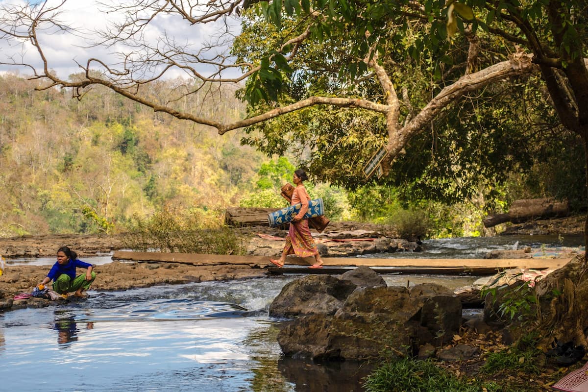 An Indigenous woman washing clothes at Bou Sra Waterfall in Mondulkiri, Cambodia. Local communities are concerned about the potential impact of six new wind farms approved in the region (Image: Brian Atkinson / Alamy)