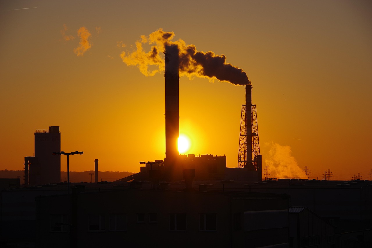 The chimney expels smoke into the sky at sunset. (Image: Pixabay)